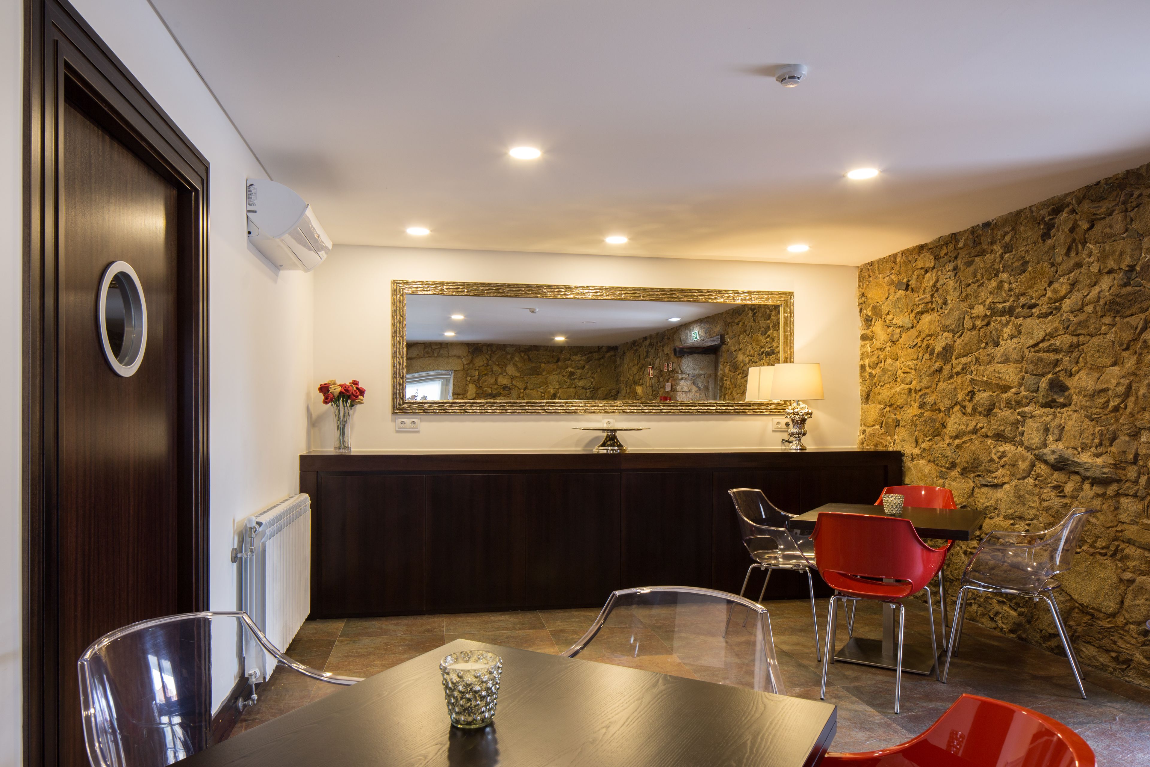 Un comedor moderno con pared de piedra, puerta de madera y espejo sobre una encimera.