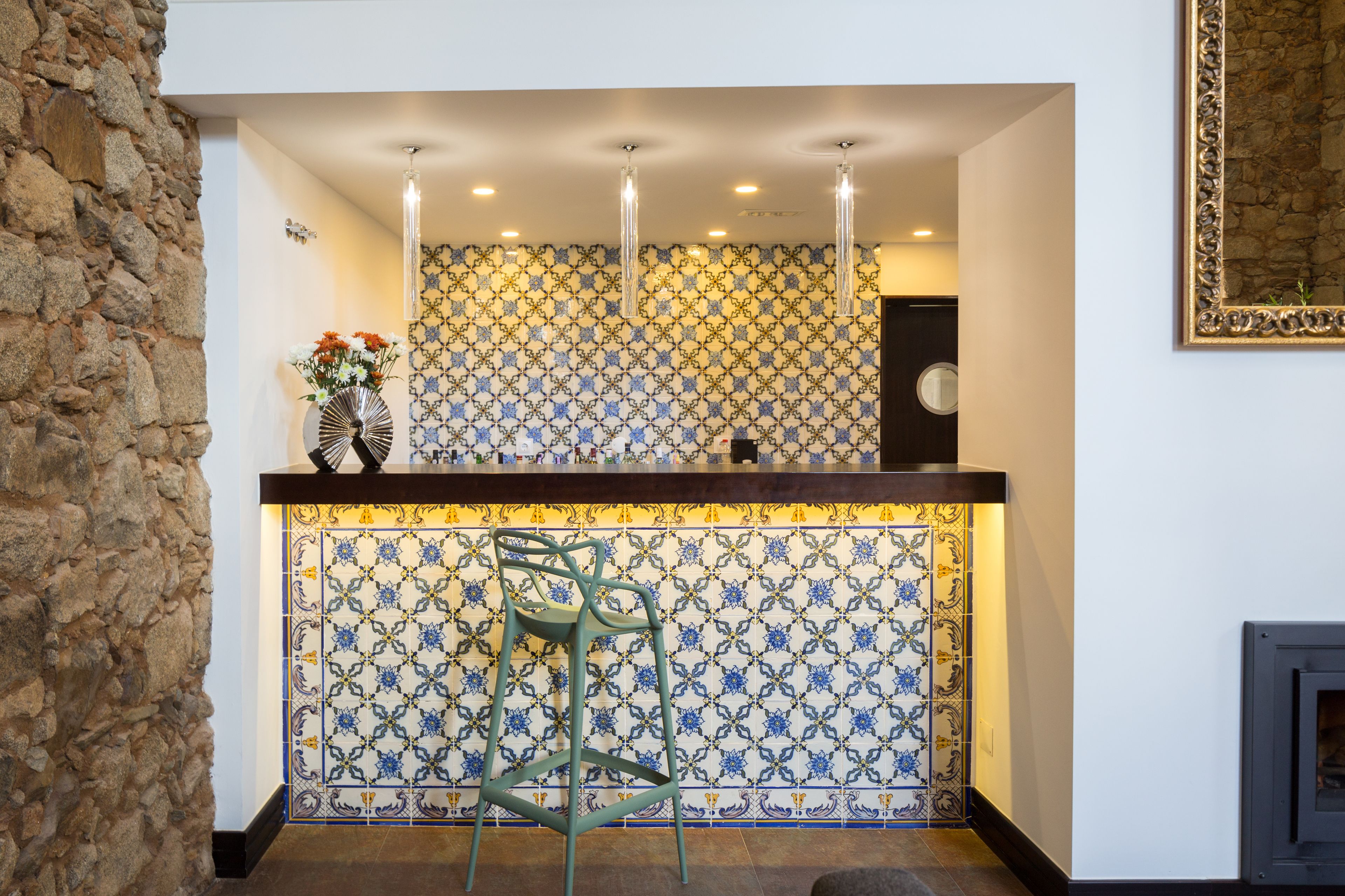 A reception area with a patterned tile wall, a wooden reception desk, and a green chair.