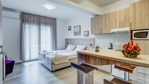 A modern hotel room with a bed, a desk, a kitchenette, and a bathroom. - Adriatik Budva apartments (Budva)