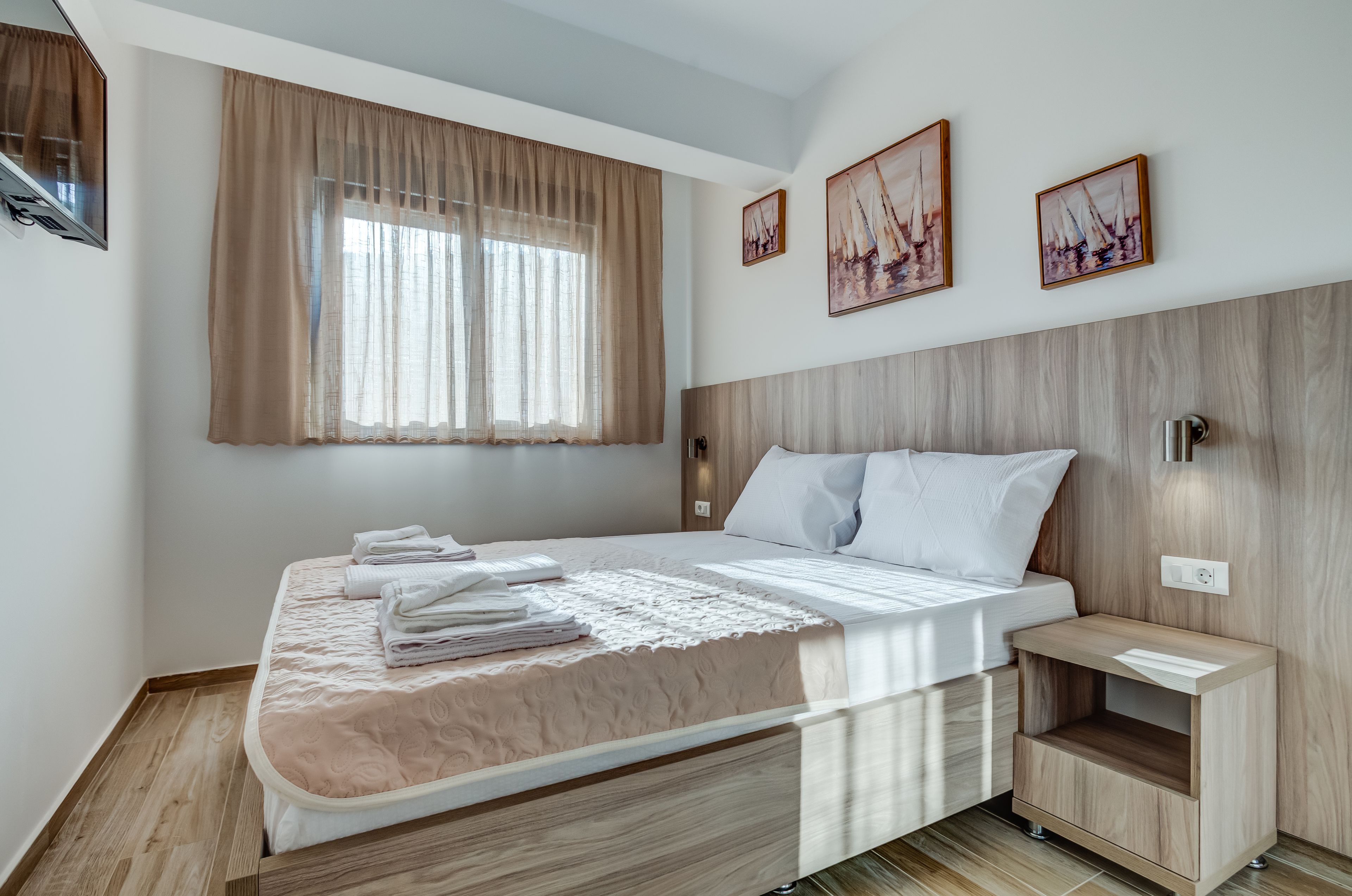 Un dormitorio moderno con una cama grande, cabecera de madera y una mesita de noche.