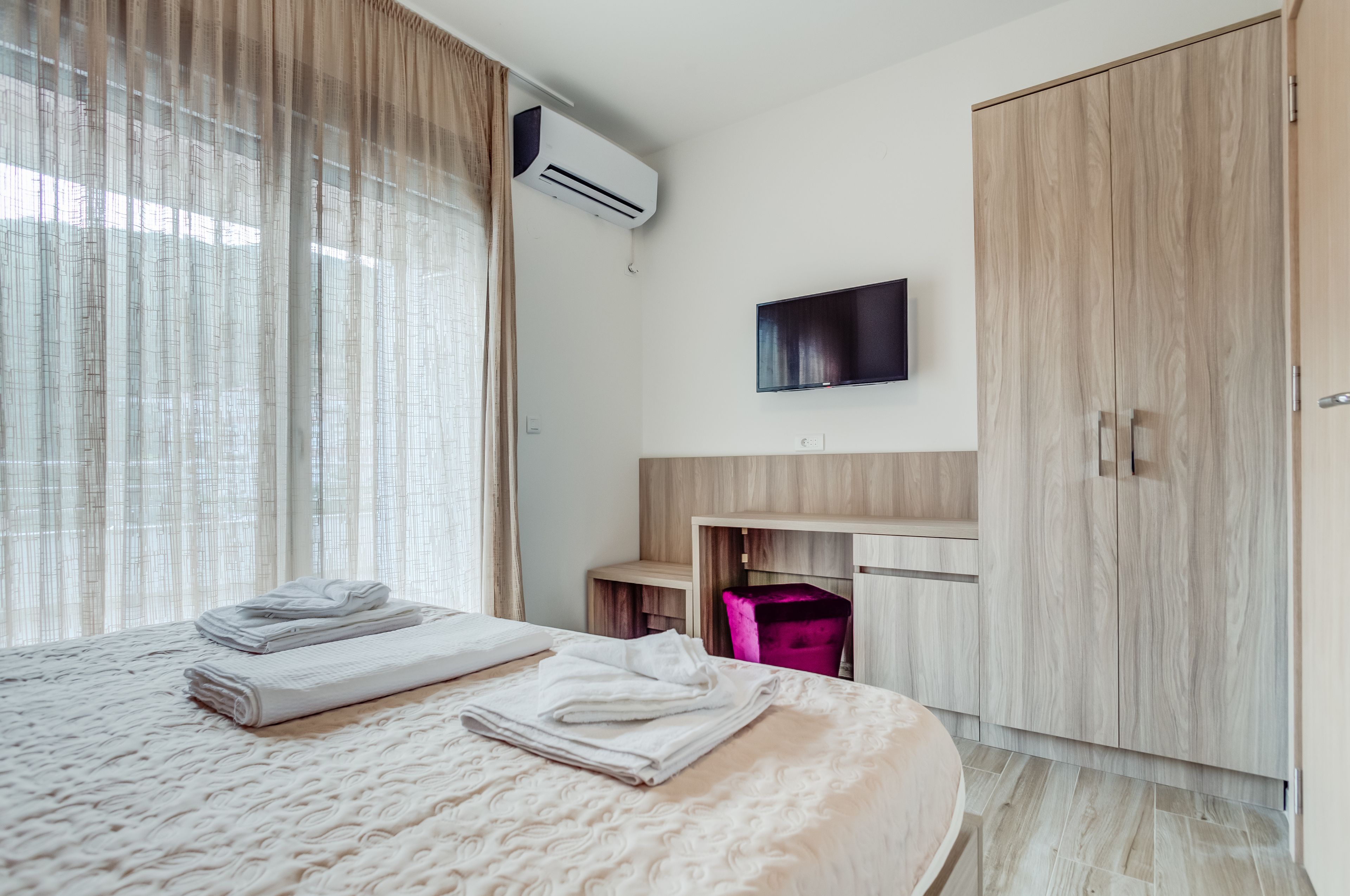 Ein modernes Hotelzimmer mit einem großen Bett, einem Schreibtisch, einem Kleiderschrank und einer Klimaanlage.
