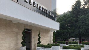 A modern building with a sign reading "AURATIK APARTMENTS". There are neatly arranged planters with greenery in front of the entrance. - Adriatik Budva apartments (Budva)