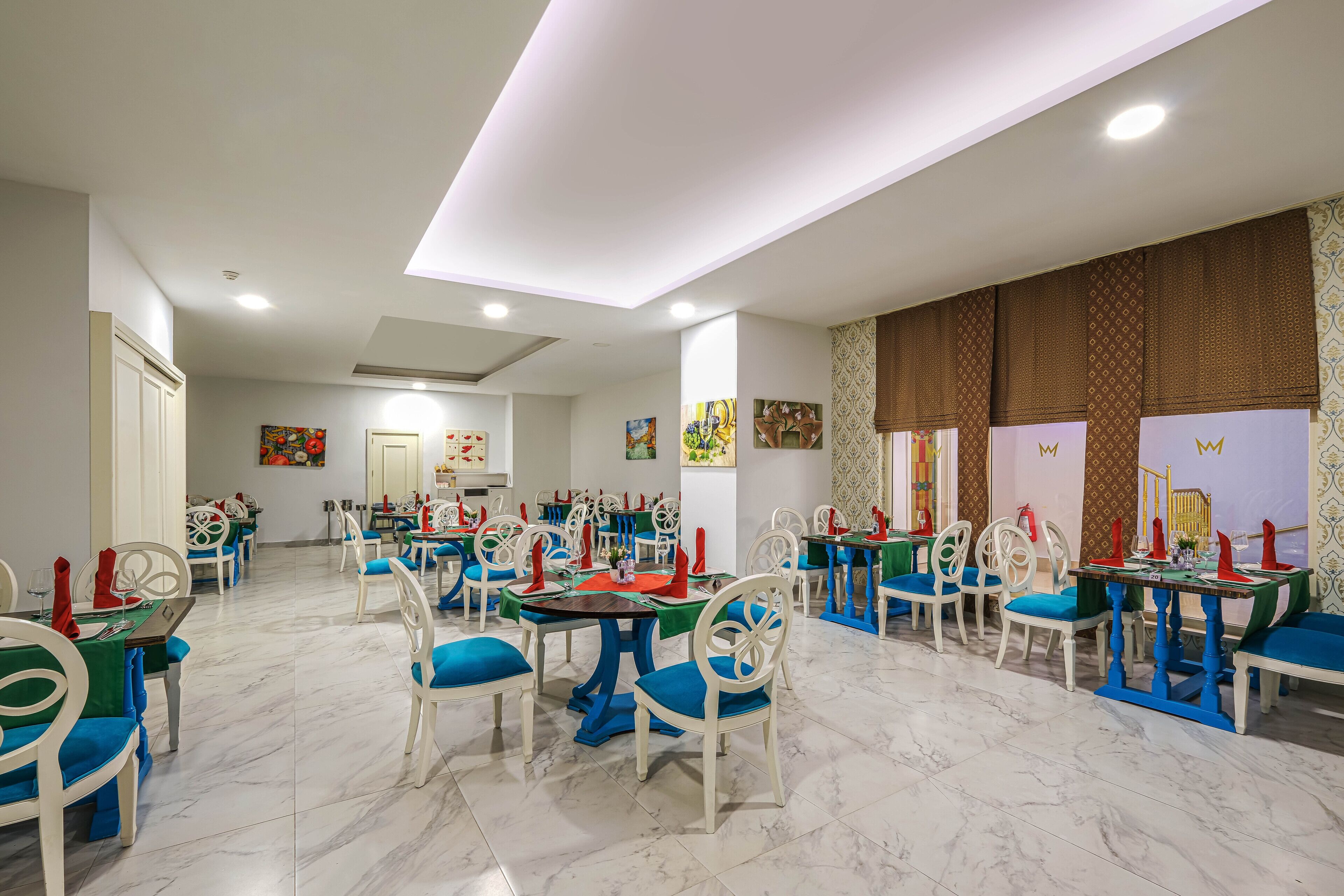 A dining area with white chairs and tables, marble flooring, and artwork on the walls.