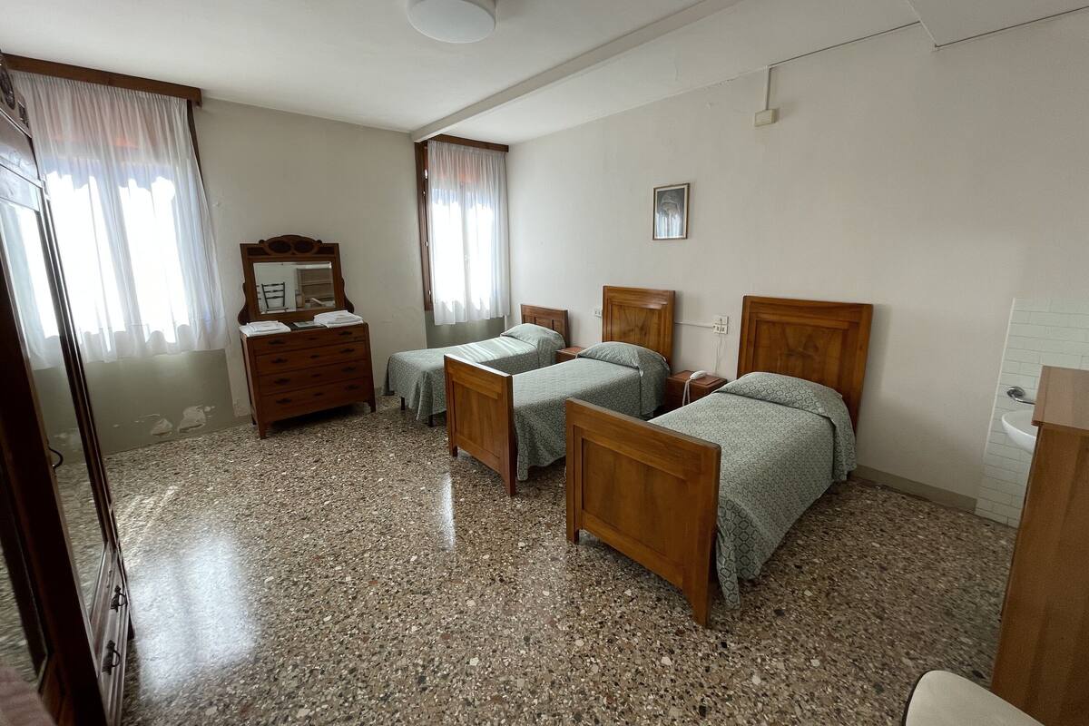 A bedroom with two single beds, a wooden dresser, a mirror, and a ceiling light.