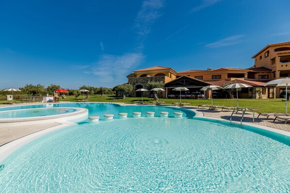 A swimming pool with a circular section and a surrounding deck with umbrellas.