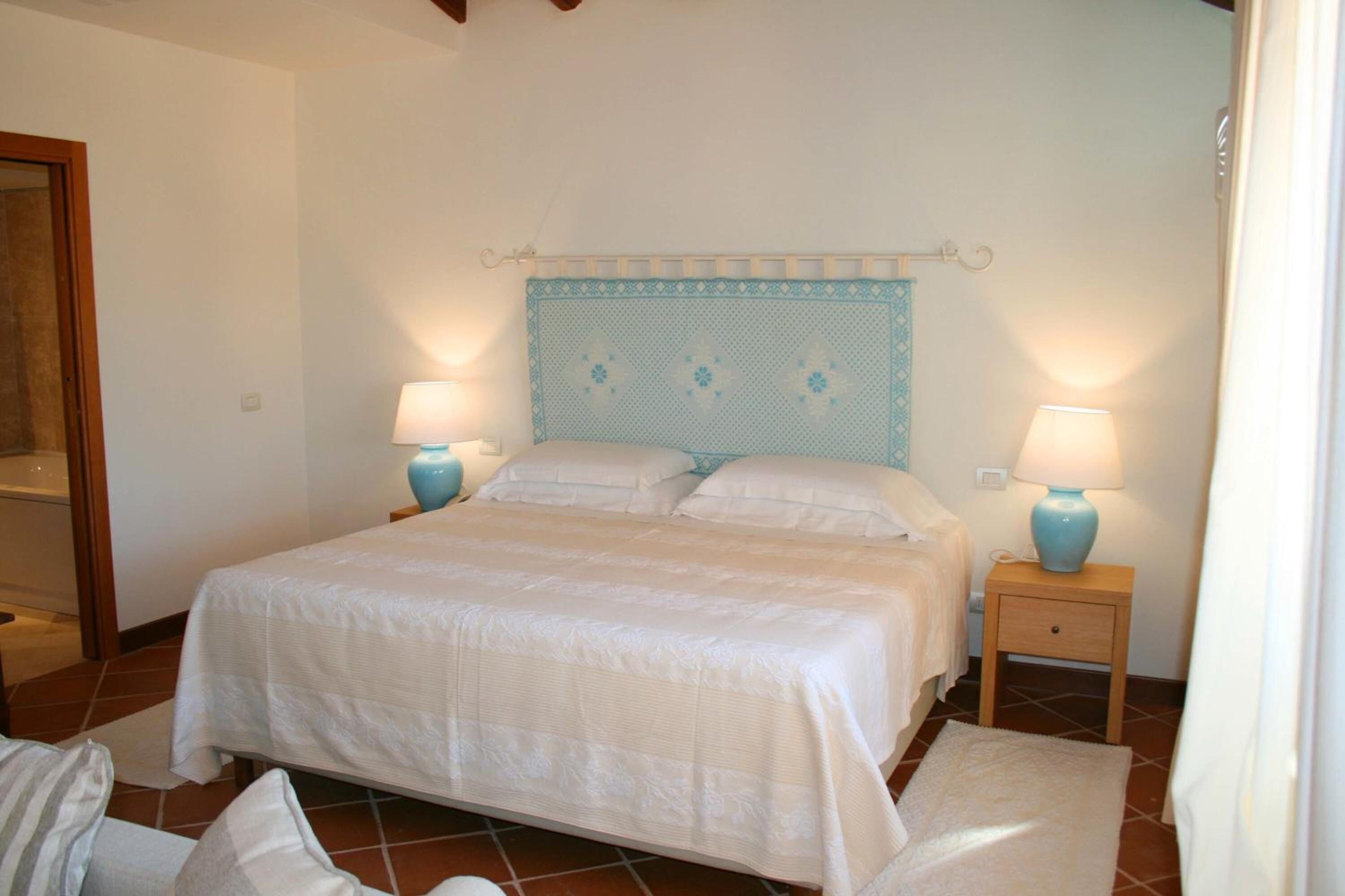 Un dormitorio con una cama, dos mesitas de noche y dos lámparas.