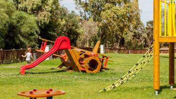 Un parque infantil con un tobogán rojo y estructuras de escalada amarillas.