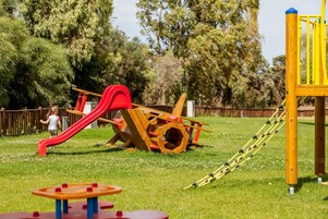 Un parque infantil con un tobogán rojo y estructuras de escalada amarillas.