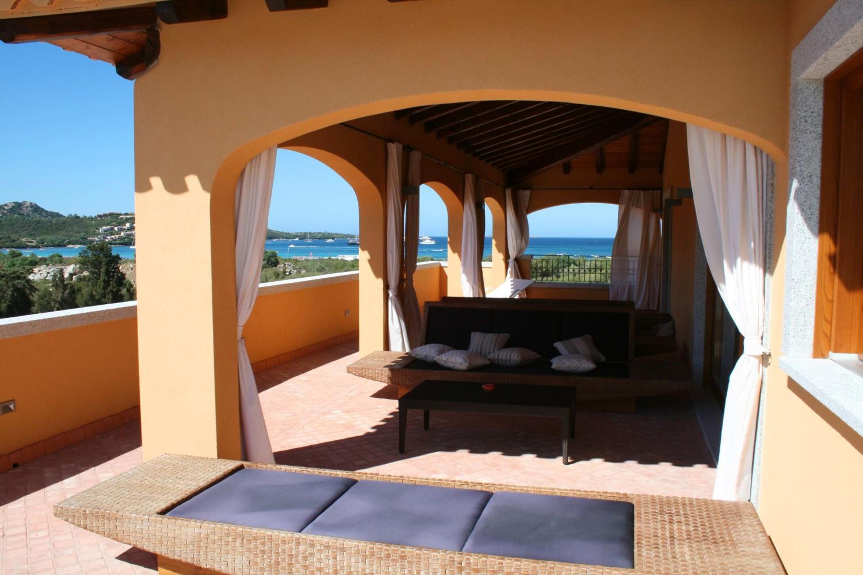 Un balcon aménagé avec un lit, un canapé et un fauteuil.