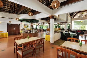 A spacious restaurant with high ceilings, wooden beams, and a variety of seating arrangements including tables and chairs.