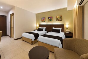 A hotel room with two beds, a small round table, a chair, and artwork on the wall. - Sunday Kuantan Near Cherating Beach Formerly Residence Inn (Cherating)