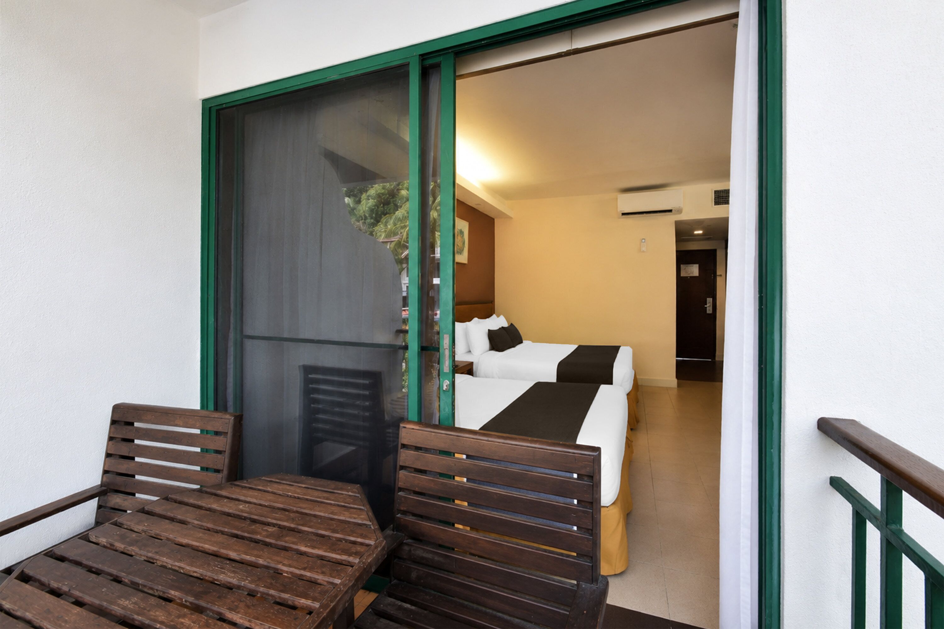 Una habitación con una cama, una mesa de madera y una silla, con un ventanal corredero que da a un espacio exterior.