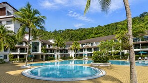 A resort with a central pool, palm trees, and a mountainous backdrop. - Sunday Kuantan Near Cherating Beach Formerly Residence Inn (Cherating)