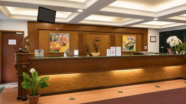 A reception desk with a flat-screen TV, wooden paneling, and artwork. - Sunday Kuantan Near Cherating Beach Formerly Residence Inn (Cherating)