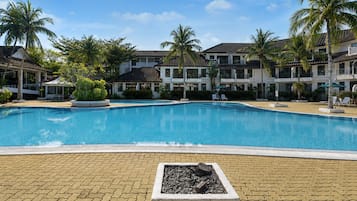Una piscina al aire libre, sombrillas, sillones reclinables de piscina