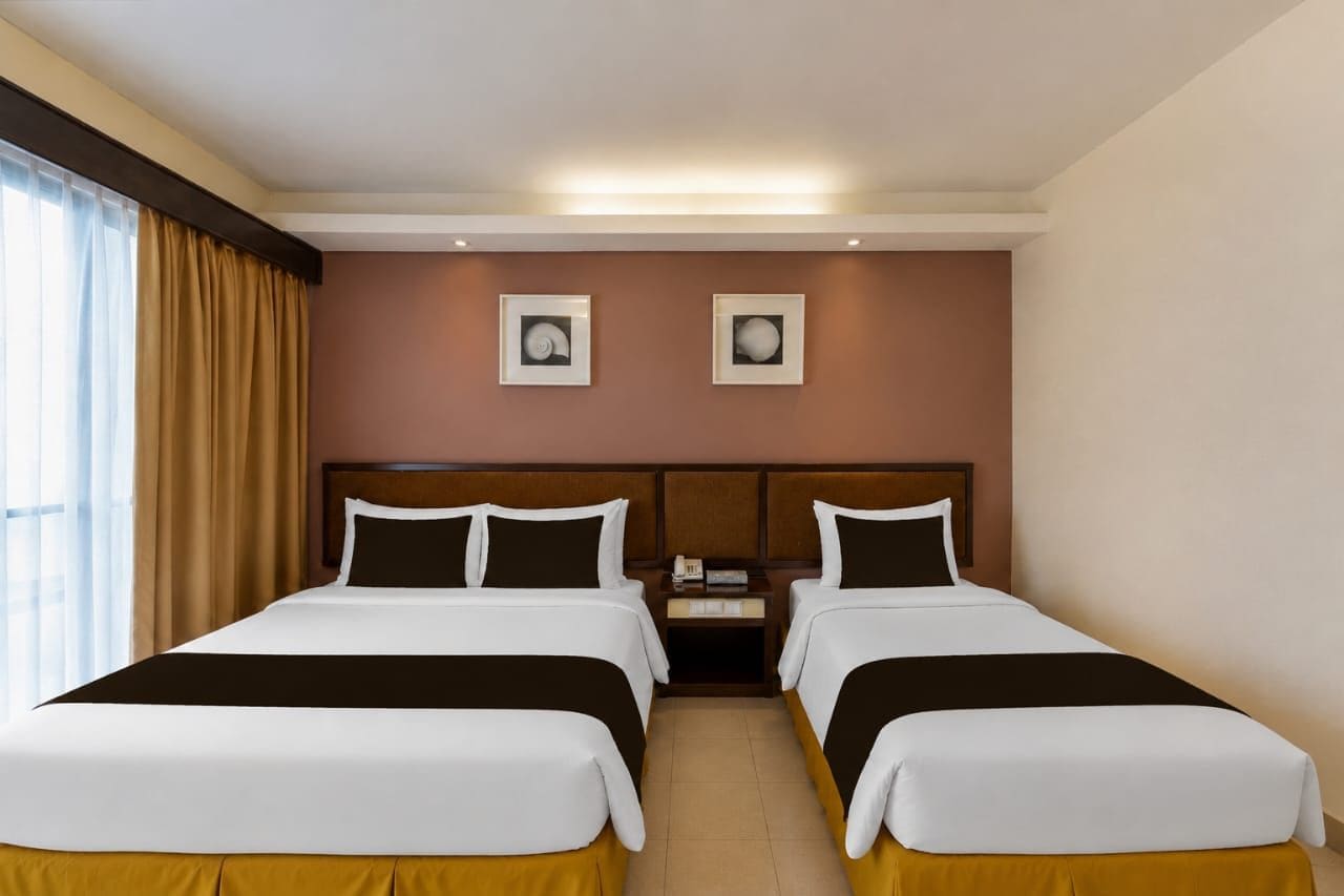 A hotel room with two beds, a nightstand, and two framed pictures on the wall.