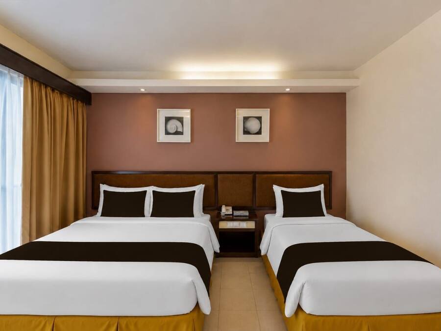 Ein Hotelzimmer mit zwei Betten, einem Nachttisch und zwei gerahmten Bildern an der Wand.