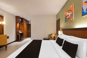 A hotel room with a large bed, a desk with a chair, a small table, and a painting on the wall. - Sunday Kuantan Near Cherating Beach Formerly Residence Inn (Cherating)