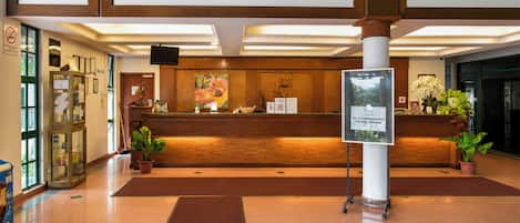 Un área de recepción con un mostrador de madera, cuadros enmarcados arriba y un cartel.