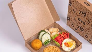 A cardboard box with a variety of food items including rice, vegetables, and a fried egg.