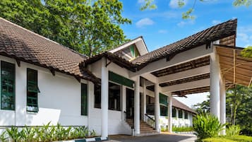 A building with a tiled roof, white walls, and green window frames.