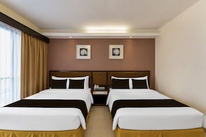 Habitación de hotel con dos camas, una mesita de noche y dos cuadros en la pared.