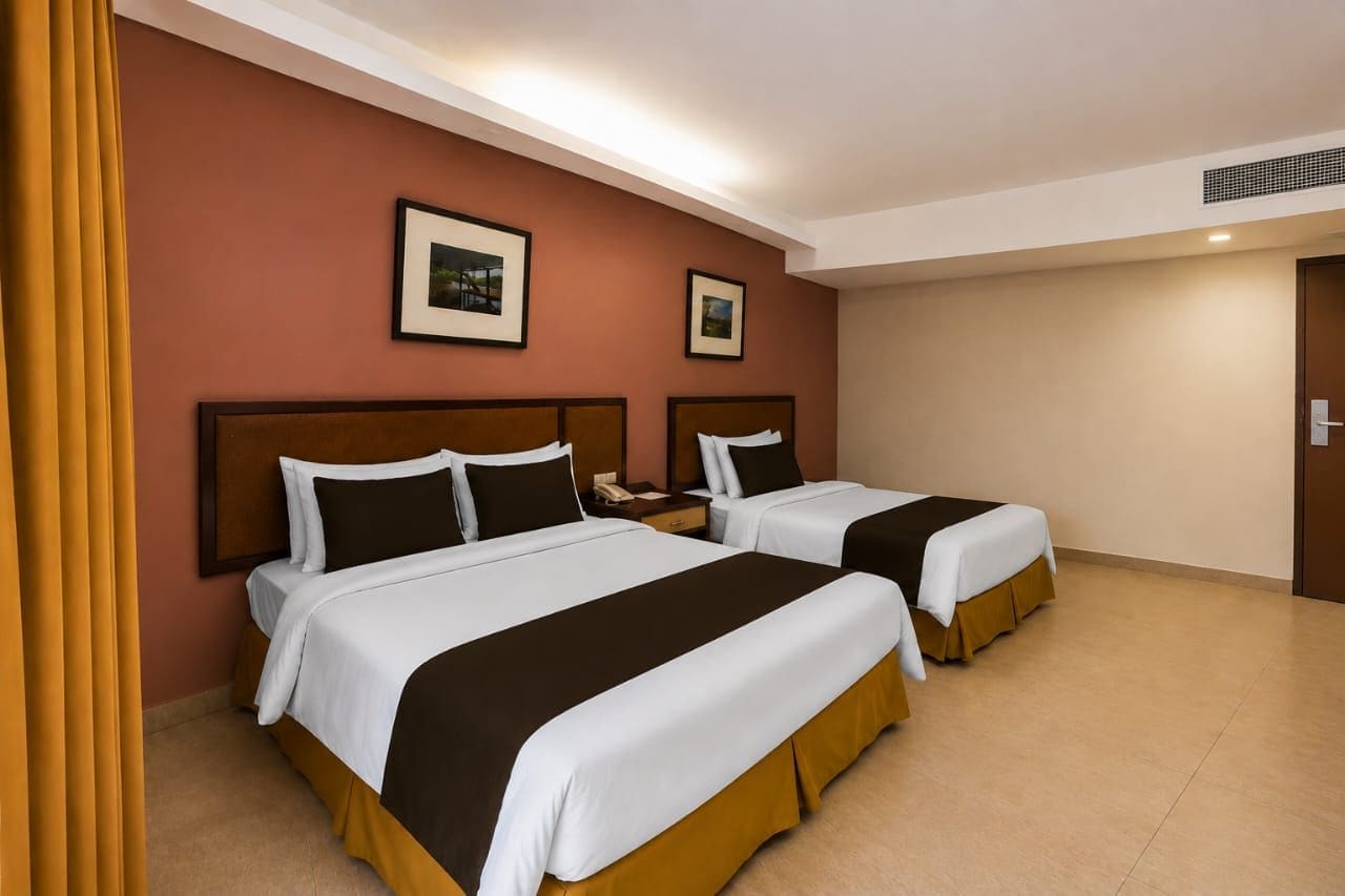 A hotel room with two beds, a brown wall, and framed pictures.
