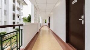 A corridor with a tiled floor, a brown door, and a white building with balconies. - Sunday Kuantan Near Cherating Beach Formerly Residence Inn (Cherating)