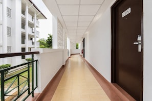 A corridor with a tiled floor, a brown door, and a white building with balconies. - Sunday Kuantan Near Cherating Beach Formerly Residence Inn (Cherating)
