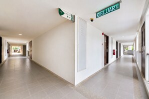 A long, well-lit corridor with directional signs, fire extinguishers, and doors on both sides. - Sunday Kuantan Near Cherating Beach Formerly Residence Inn (Cherating)
