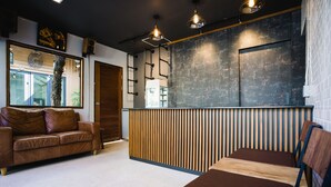 A modern interior with a wooden reception desk, a leather sofa, and a bench.