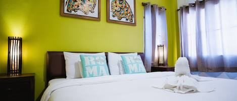 Una habitación de hotel con una cama, dos almohadas con el texto 'ROMS MAMA', dos cuadros enmarcados en la pared y una toalla sobre la cama.