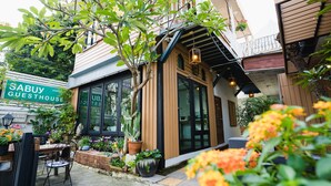 A guesthouse with a wooden facade, large windows, and a sign reading "SABUY GUESTHOUSE".