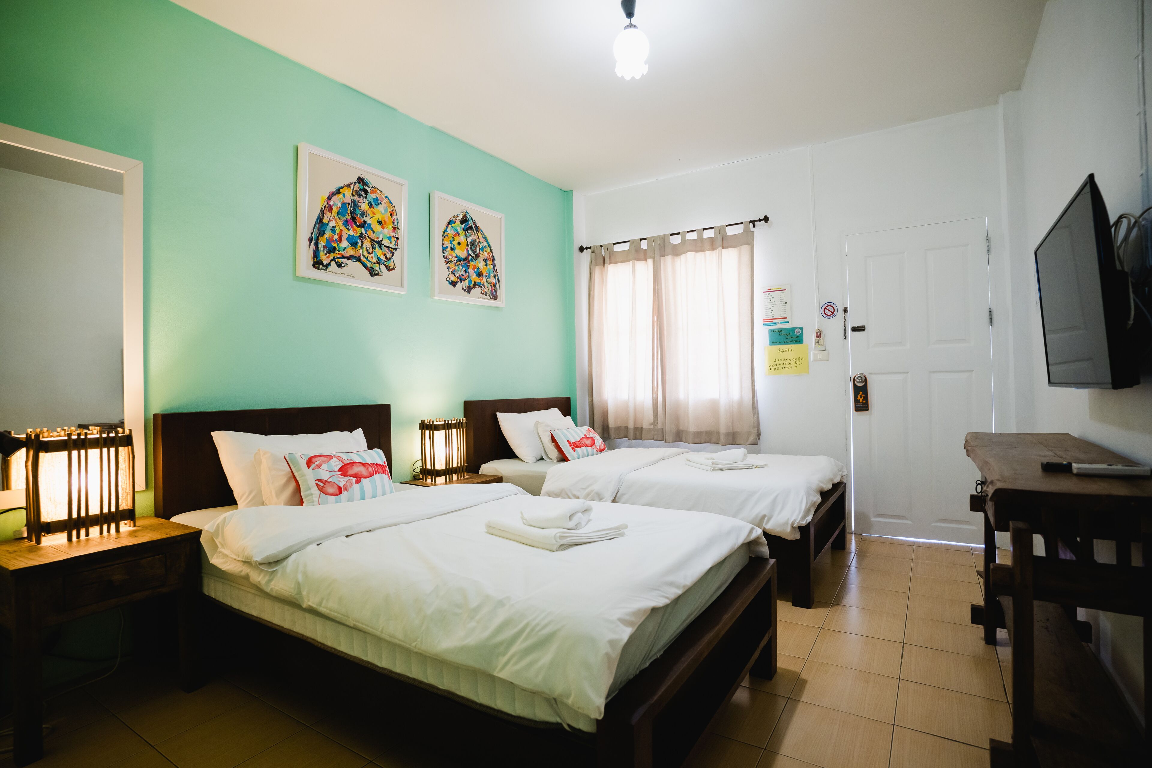 A hotel room with two beds, a TV, and artwork on the wall.