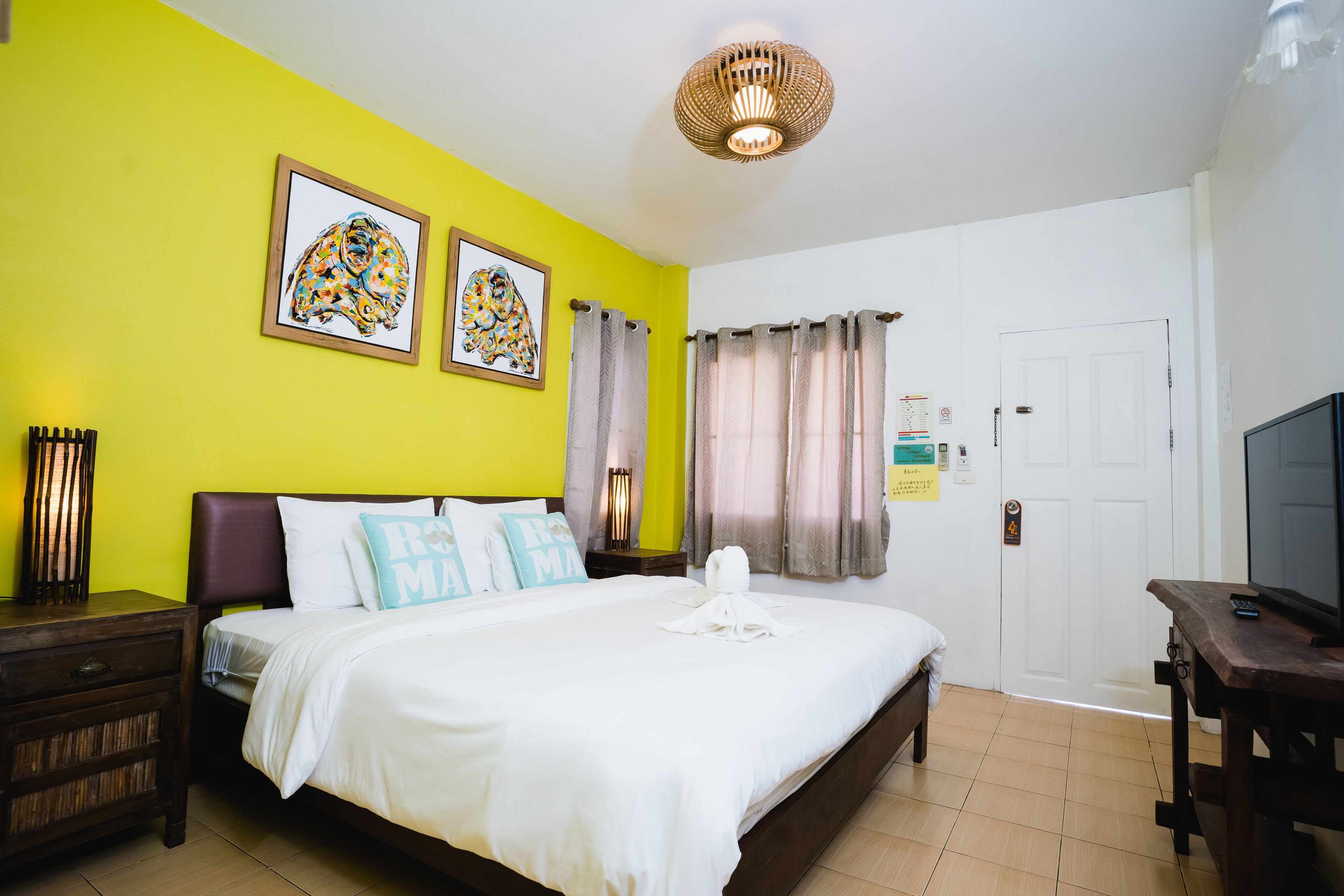 Una habitación de hotel con cama, mesita de noche, televisión y obras de arte en la pared.