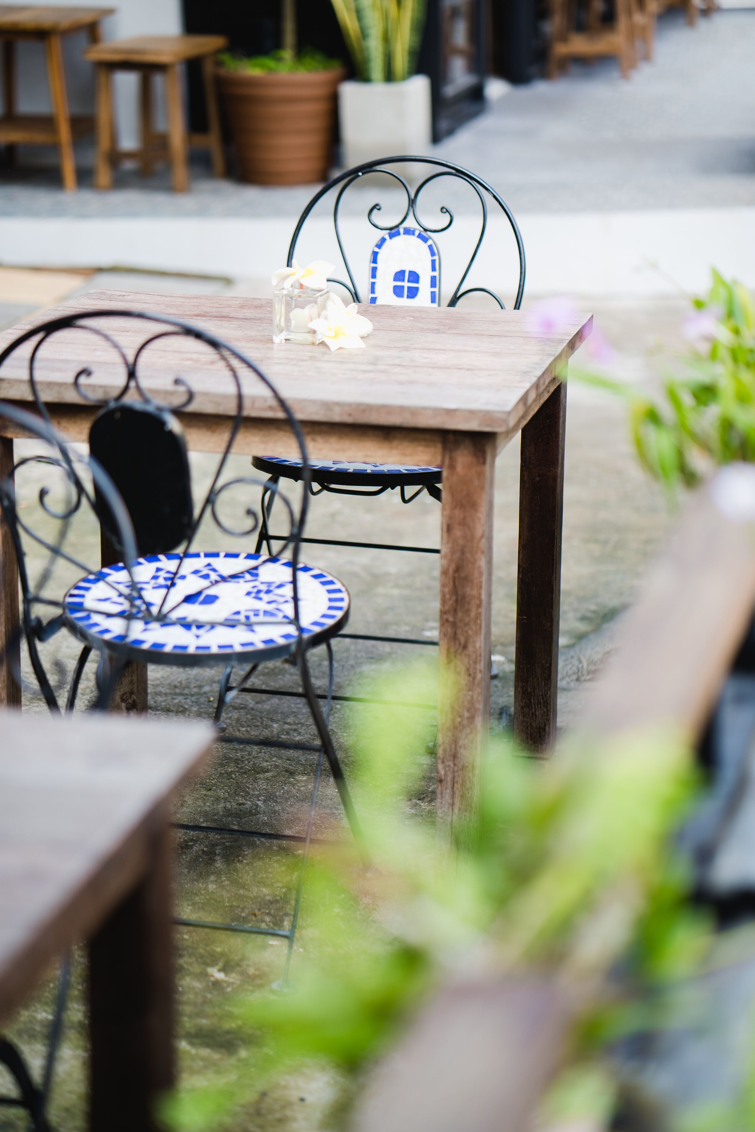 Una mesa de madera con una silla de estampado azul y blanco, un vaso de agua y una planta en maceta al fondo.