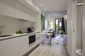 Une cuisine moderne avec des meubles blancs, un four encastré et un coin repas comprenant une table et des chaises.