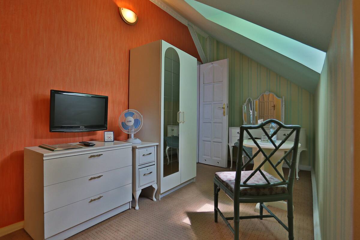 Ein Schlafzimmer mit Fernseher, Kommode und Stuhl.
