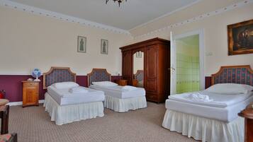 A hotel room with two single beds, a wooden wardrobe, a mirror, and a door leading to a bathroom.