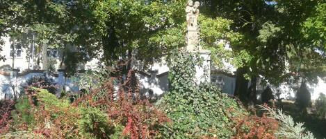Un jardin agrémenté d’une statue, entouré d’arbres et d’arbustes.