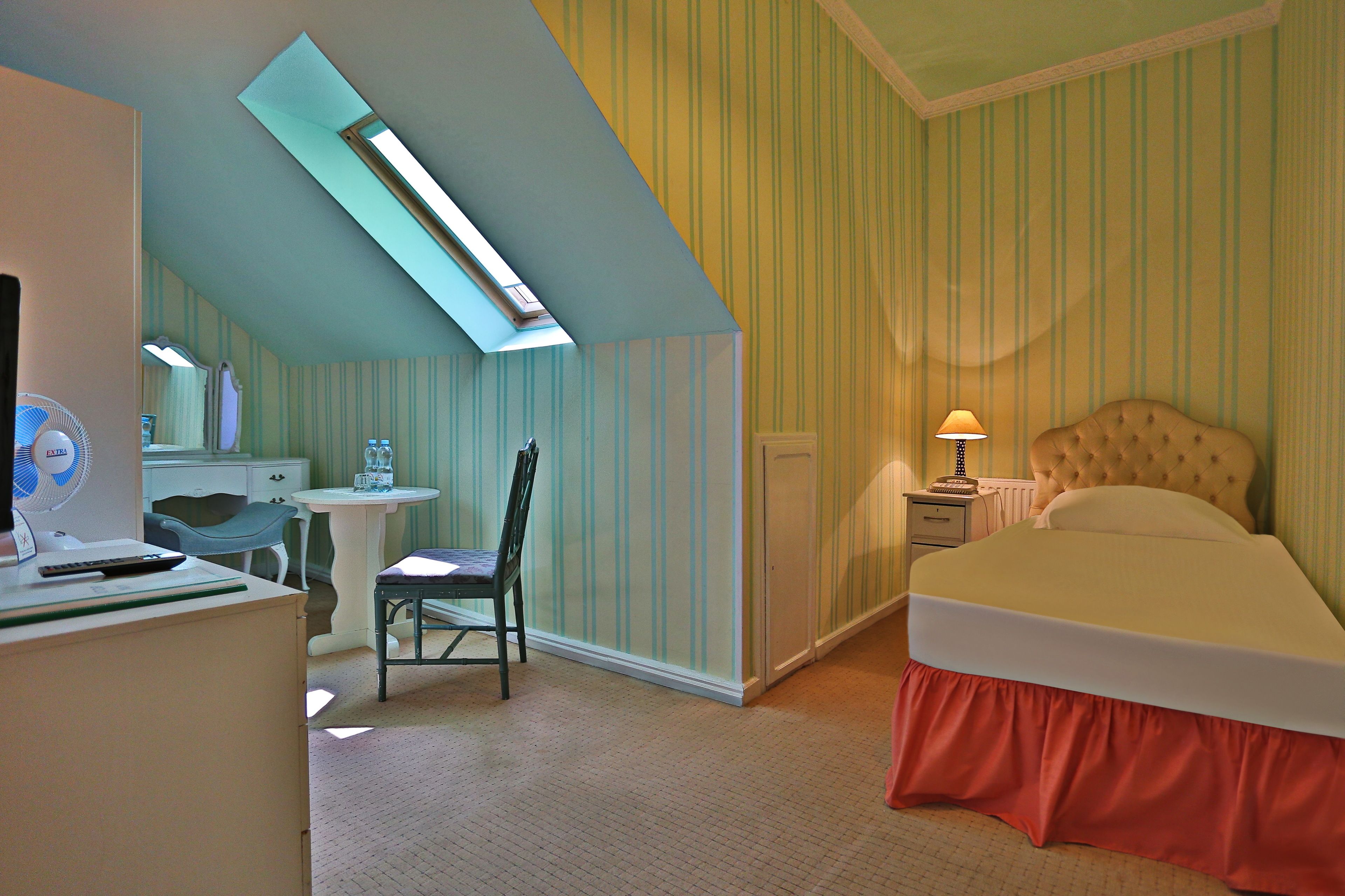 Ein Schlafzimmer mit einem Bett, einem Schreibtisch, einem Stuhl, einer Schreibtischlampe und einem Fenster.