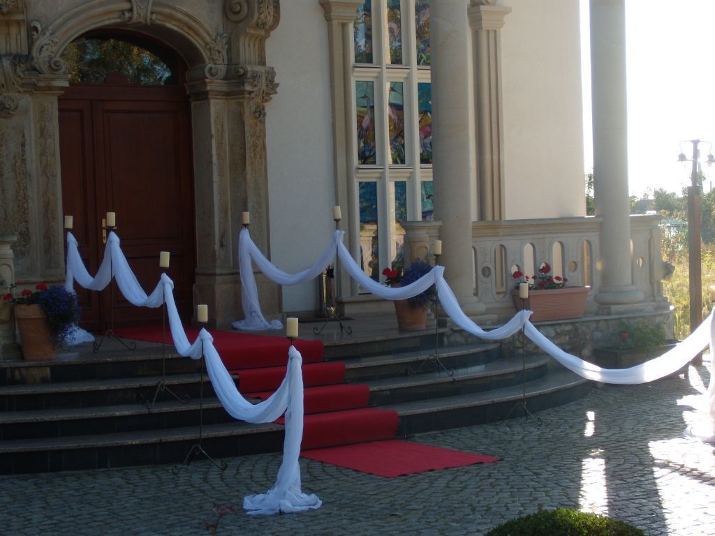 A building entrance with a red carpet, white drapes, and a white rope barrier.