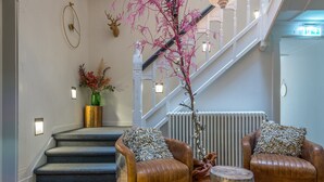 A modern interior with a staircase, leather armchairs, a decorative plant, and a radiator.