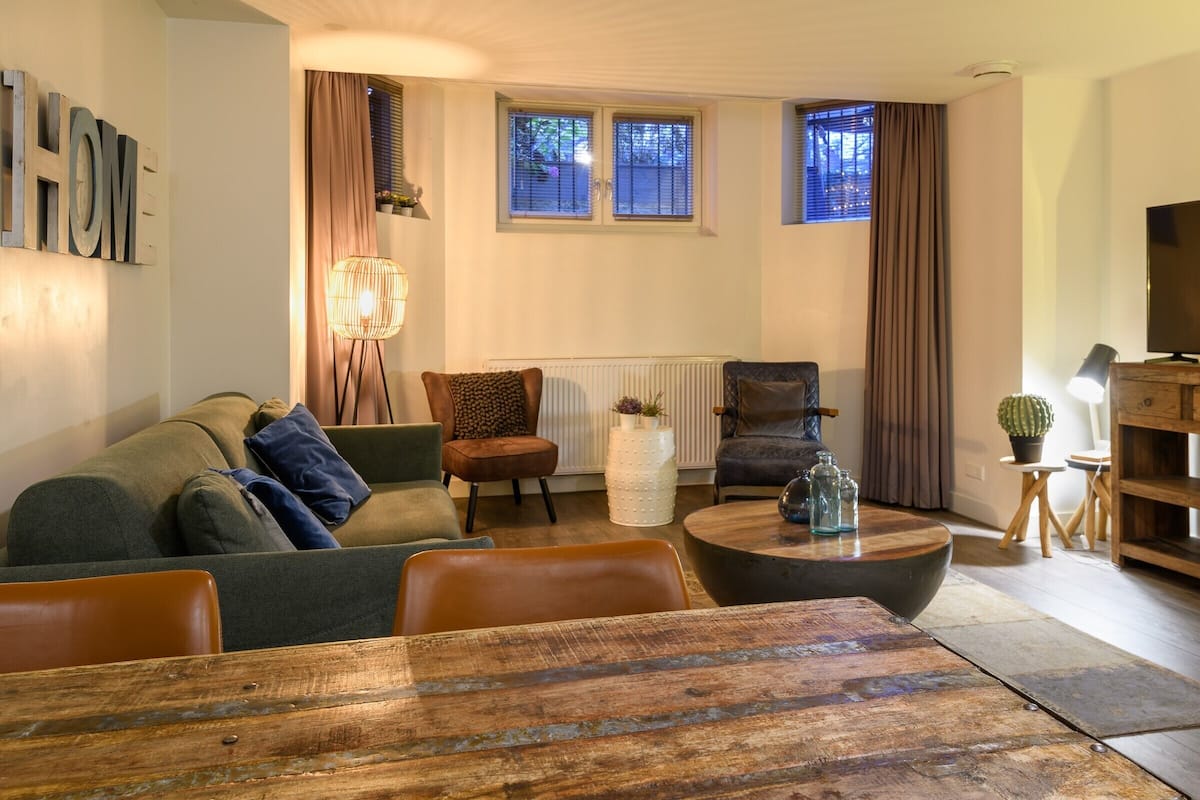 Een woonkamer met een bank, fauteuils, een salontafel en een televisie.