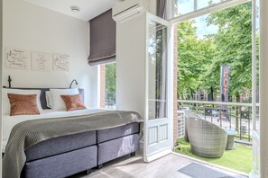 Een slaapkamer met een groot bed, uitzicht op het landschap en een balkon met tuinmeubilair.