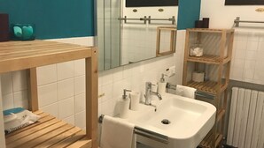 Un baño con tocador de madera, lavamanos, espejo y perchero para toallas.
