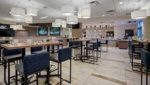 A modern hotel lobby with multiple seating areas, a reception desk, and a large screen displaying a scenic image. - Best Western Plus Sawridge Suites (Fort McMurray)