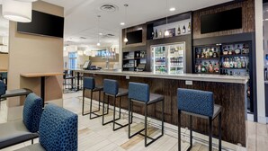 A modern bar area with a counter, bar stools, and a variety of liquor bottles. - Best Western Plus Sawridge Suites (Fort McMurray)
