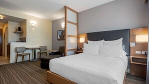 A hotel room with a large bed, a desk with two chairs, a small table, and a kitchenette. - Best Western Plus Sawridge Suites (Fort McMurray)