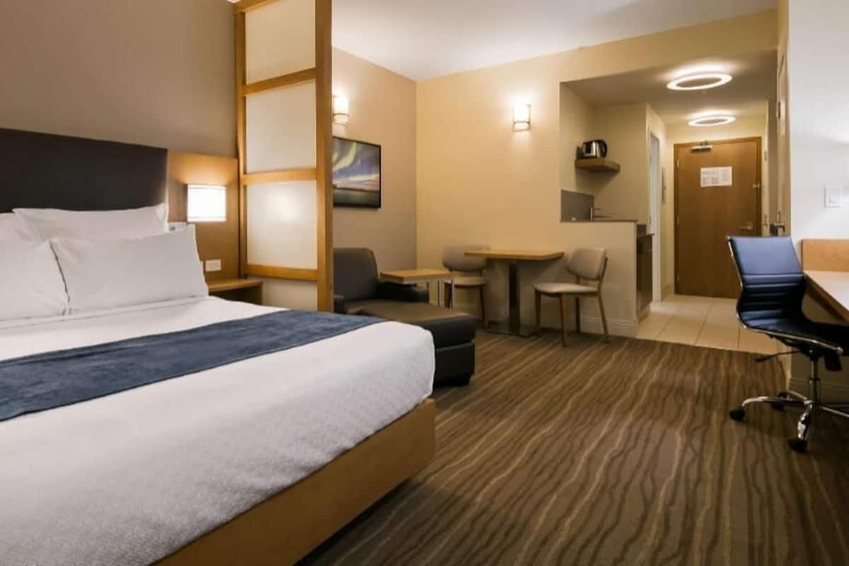 A hotel room with a bed, a desk, a chair, and a small table.